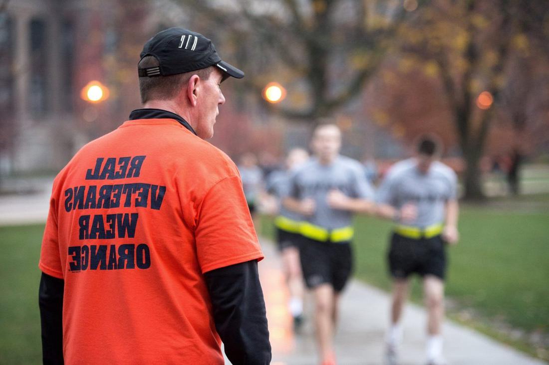 后备军官训练队的学生们在院子里跑着，后面跟着一个男人，他穿着一件t恤，上面写着:“真正的退伍军人穿橙色。”