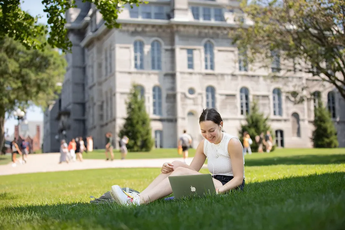 学生坐在草地上玩笔记本电脑.
